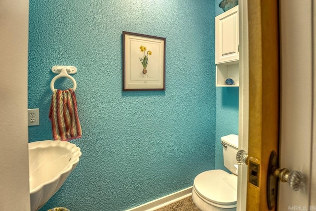 bathroom featuring toilet and a textured wall