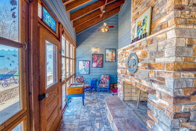 interior space with a healthy amount of sunlight, vaulted ceiling with beams, ceiling fan, and stone finish floor
