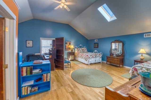 bedroom featuring baseboards, visible vents, a ceiling fan, lofted ceiling with skylight, and wood finished floors