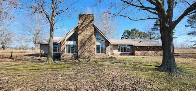 rear view of house with stone siding and a lawn