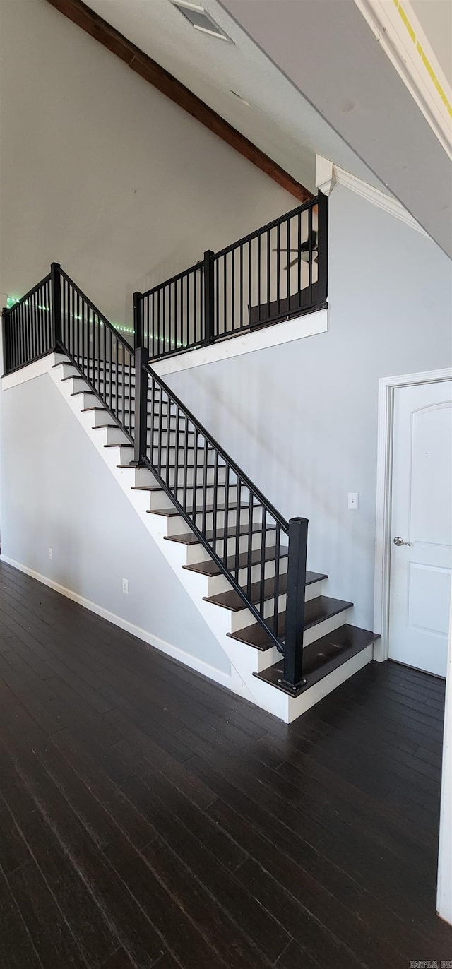 stairs featuring high vaulted ceiling, wood finished floors, beam ceiling, and baseboards