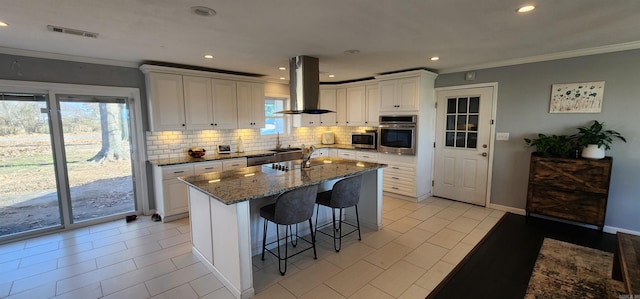 kitchen featuring stainless steel appliances, a breakfast bar, ornamental molding, backsplash, and island exhaust hood