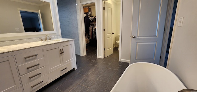 bathroom with wood finish floors, a soaking tub, a spacious closet, toilet, and vanity