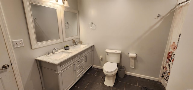 full bath with toilet, double vanity, baseboards, and a sink