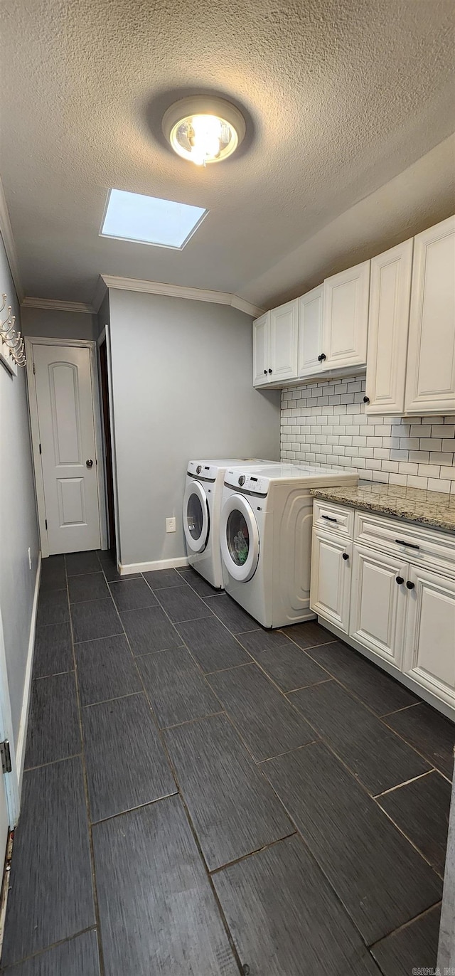 laundry area featuring baseboards, cabinet space, a textured ceiling, and washing machine and clothes dryer