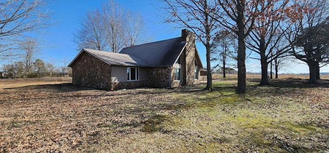 view of side of home with stone siding and a chimney