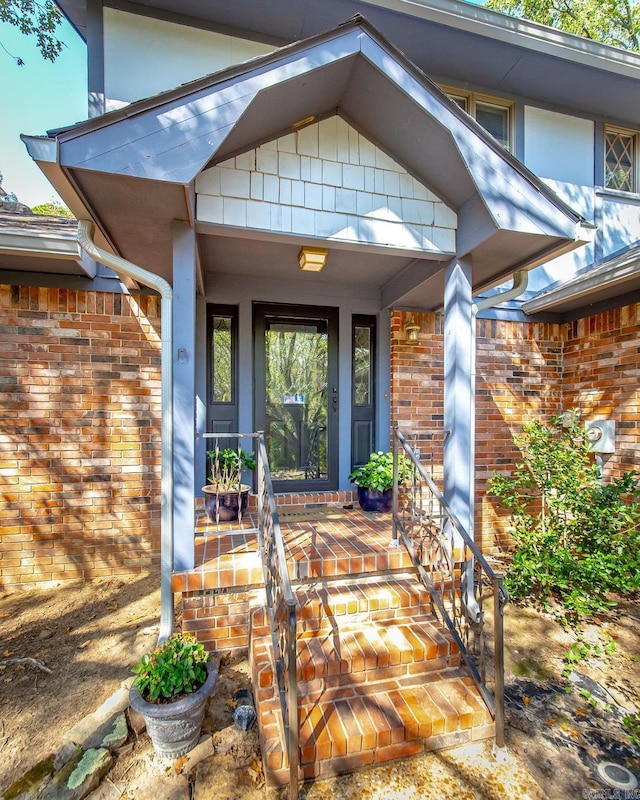 entrance to property featuring covered porch and brick siding