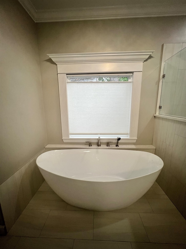 full bath with ornamental molding, a wealth of natural light, and a freestanding tub