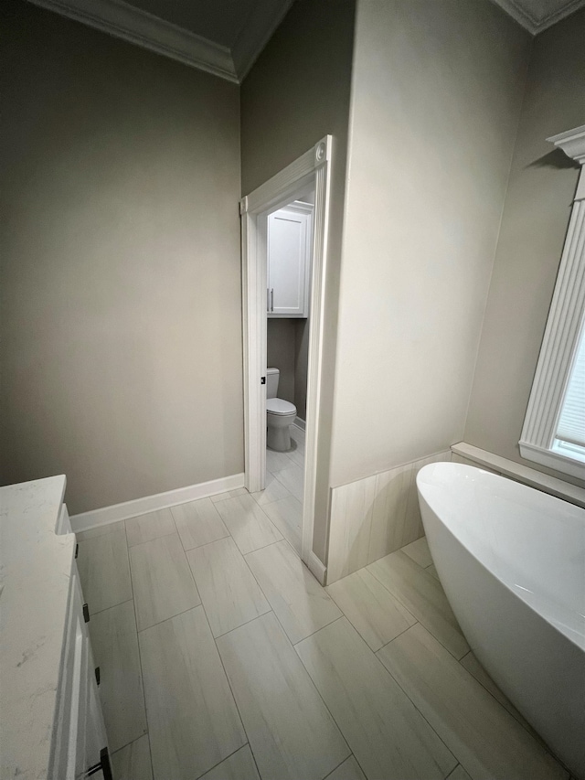 full bath with toilet, a freestanding tub, baseboards, and crown molding