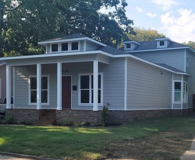 view of front of home with covered porch, stone siding, and a front lawn