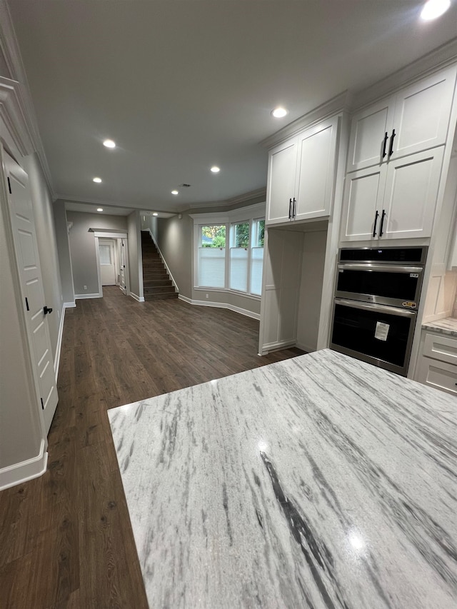 kitchen with double oven, recessed lighting, white cabinets, light stone countertops, and dark wood-style floors