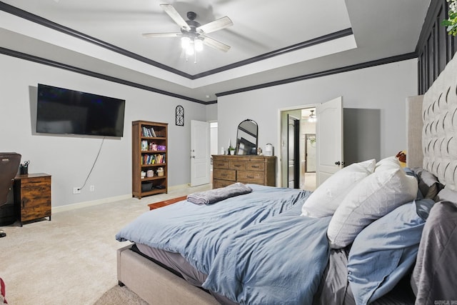 carpeted bedroom with crown molding, a raised ceiling, connected bathroom, ceiling fan, and baseboards