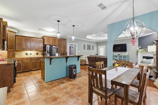 dining area with a tray ceiling, a fireplace, light tile patterned floors, visible vents, and a chandelier