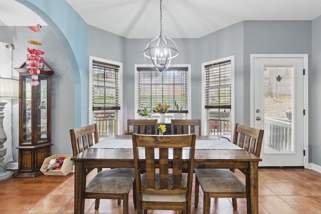 dining area with light tile patterned floors, baseboards, and an inviting chandelier