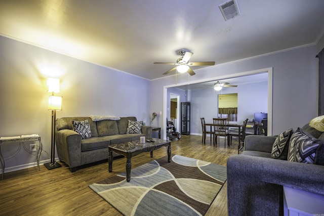 living area featuring visible vents, ornamental molding, baseboards, and wood finished floors