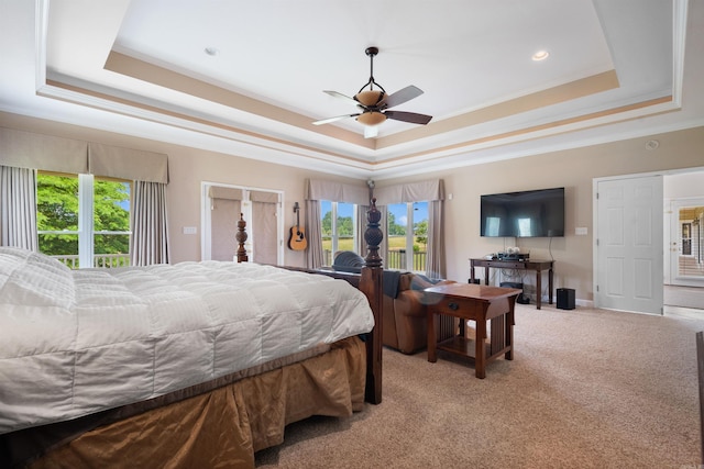 bedroom featuring a tray ceiling, multiple windows, light colored carpet, and crown molding