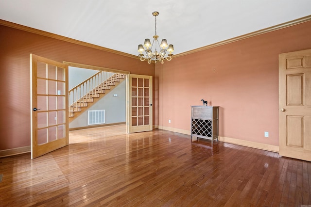 empty room with visible vents, french doors, crown molding, and hardwood / wood-style flooring