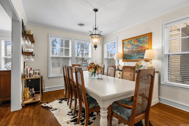 dining space featuring baseboards, wood finished floors, visible vents, and ornamental molding