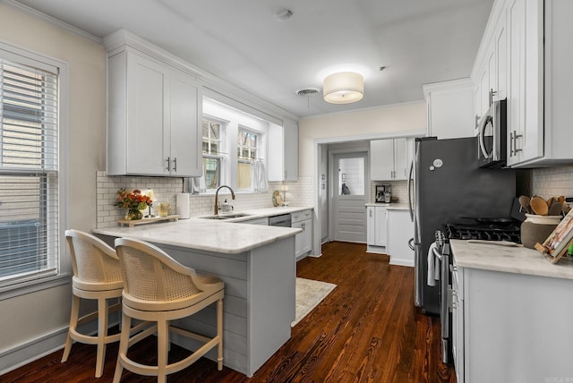 kitchen with dark wood-style floors, appliances with stainless steel finishes, a peninsula, and white cabinets