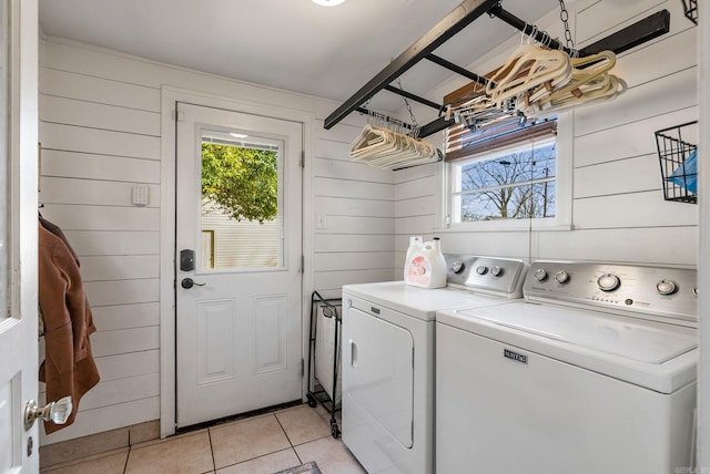 washroom featuring washing machine and clothes dryer, laundry area, wood walls, and light tile patterned flooring