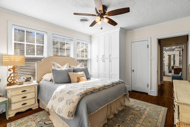 bedroom featuring visible vents, ornamental molding, a textured ceiling, a closet, and dark wood-style flooring