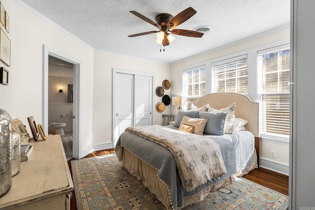 bedroom featuring visible vents, dark wood-type flooring, a closet, a textured ceiling, and crown molding