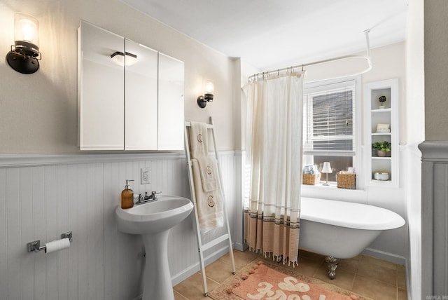 bathroom featuring tile patterned floors, a wainscoted wall, and a soaking tub