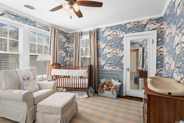 bedroom featuring wallpapered walls, crown molding, and wainscoting