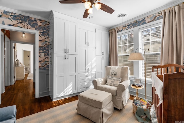 sitting room with visible vents, dark wood-type flooring, wallpapered walls, wainscoting, and crown molding