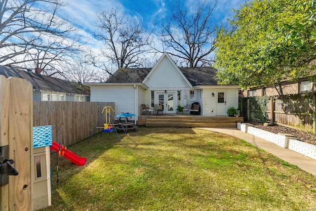 rear view of house with french doors, a deck, a lawn, and a fenced backyard