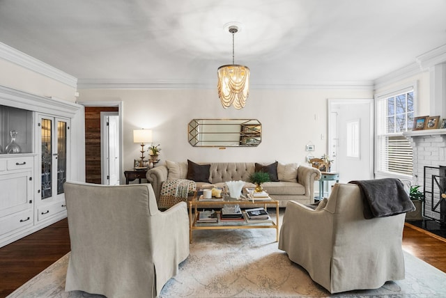 living room featuring a fireplace, crown molding, wood finished floors, and a chandelier