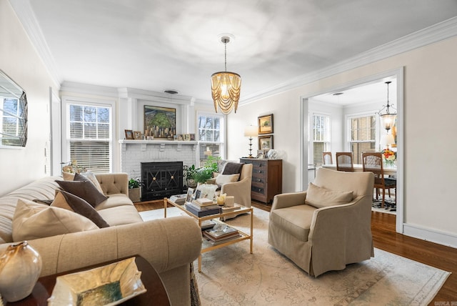 living room featuring a fireplace, an inviting chandelier, wood finished floors, and a healthy amount of sunlight