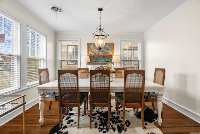 dining space with visible vents, baseboards, wood finished floors, and crown molding