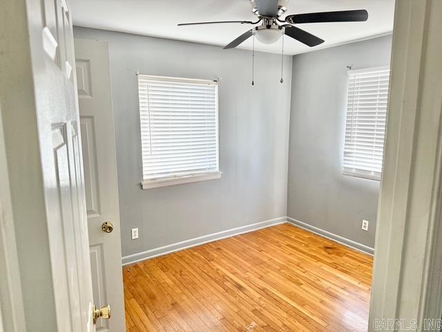 spare room featuring baseboards, ceiling fan, and light wood finished floors