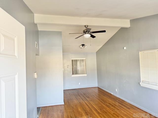 empty room featuring ceiling fan, vaulted ceiling with beams, baseboards, and wood finished floors