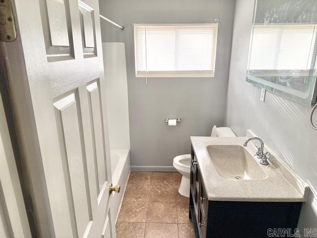 bathroom featuring vanity, shower / tub combination, toilet, and baseboards