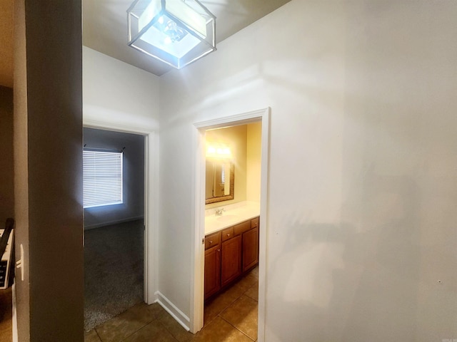 hall featuring tile patterned floors, carpet flooring, and a sink