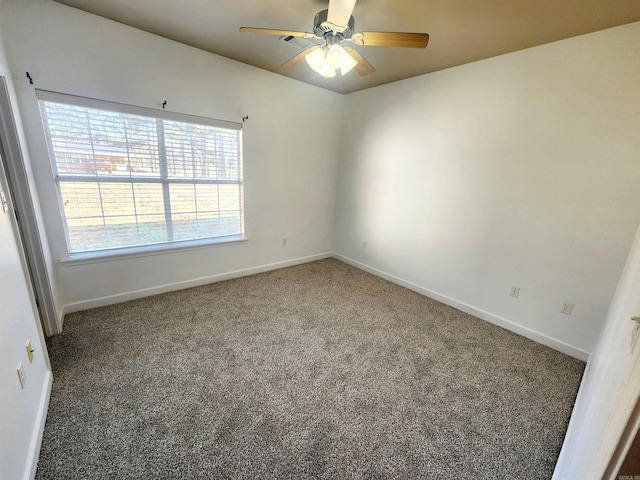 carpeted spare room featuring ceiling fan and baseboards