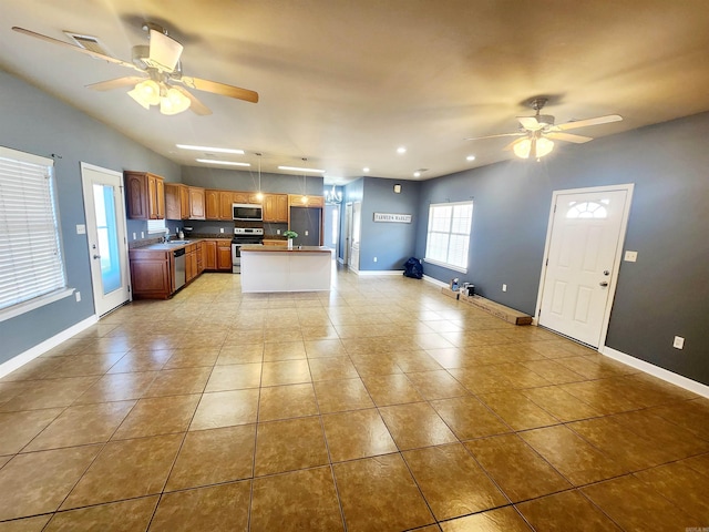 kitchen featuring open floor plan, ceiling fan, stainless steel appliances, and baseboards