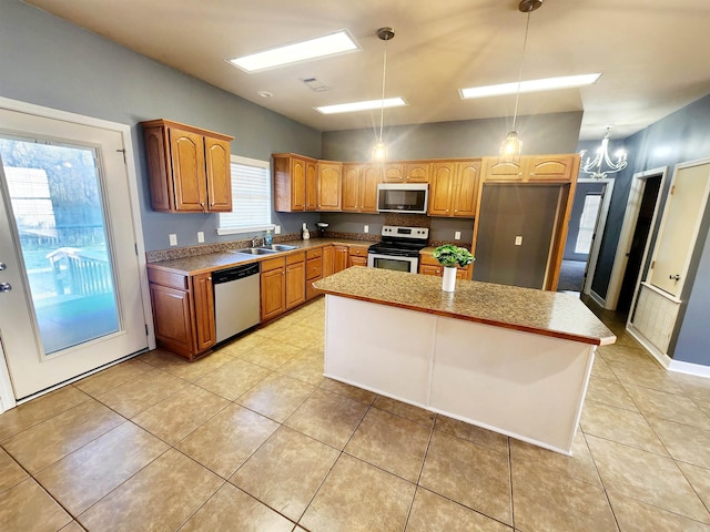 kitchen featuring light tile patterned floors, a sink, stainless steel appliances, decorative light fixtures, and a center island