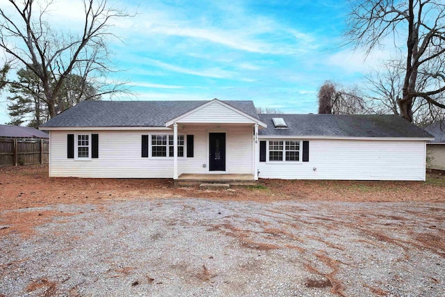 ranch-style house featuring a porch, fence, and a shingled roof