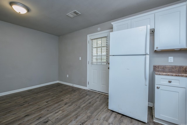 kitchen featuring visible vents, dark wood-style floors, white cabinetry, freestanding refrigerator, and baseboards