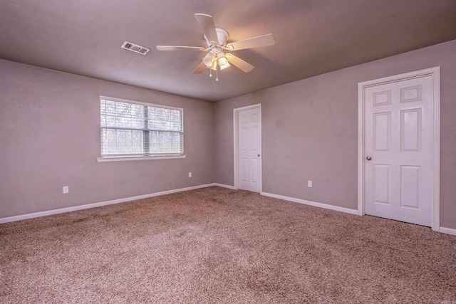 empty room featuring baseboards, visible vents, carpet floors, and ceiling fan