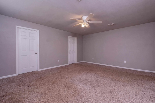 carpeted spare room with visible vents, baseboards, and a ceiling fan