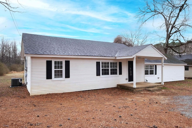 ranch-style house with cooling unit, roof with shingles, and a patio