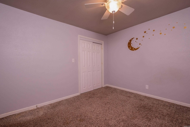 carpeted spare room featuring ceiling fan and baseboards