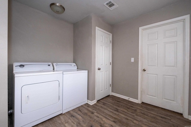 laundry area featuring wood finished floors, baseboards, visible vents, washing machine and clothes dryer, and laundry area