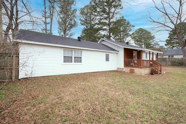 rear view of house featuring a yard and fence