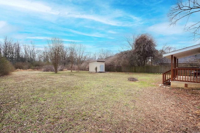 view of yard featuring an outdoor structure, fence, a shed, and an outdoor fire pit