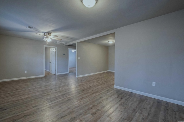 spare room featuring ceiling fan, visible vents, baseboards, and wood finished floors